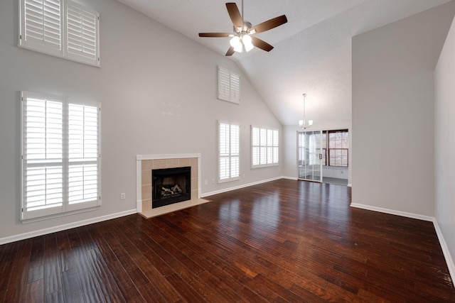 unfurnished living room with hardwood / wood-style flooring, a fireplace, high vaulted ceiling, baseboards, and ceiling fan with notable chandelier