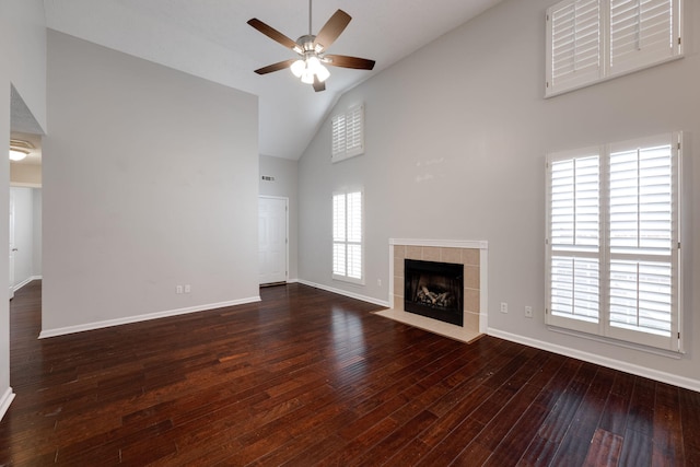 unfurnished living room with a fireplace, dark wood finished floors, a ceiling fan, high vaulted ceiling, and baseboards