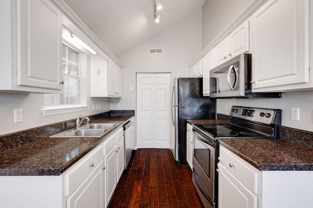 kitchen featuring visible vents, appliances with stainless steel finishes, vaulted ceiling, white cabinetry, and a sink