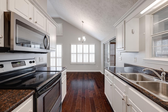 kitchen with stainless steel appliances, dark countertops, white cabinets, and vaulted ceiling