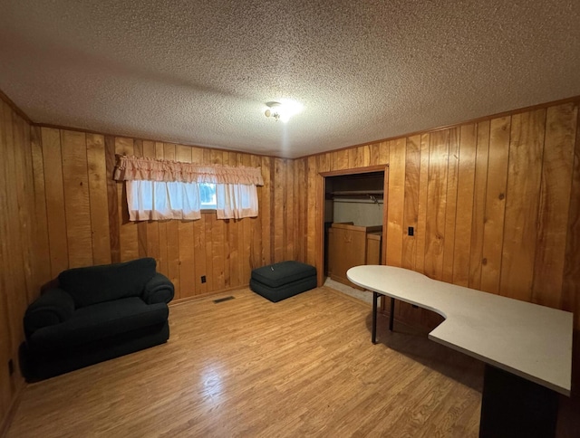 sitting room with hardwood / wood-style flooring, wooden walls, and a textured ceiling