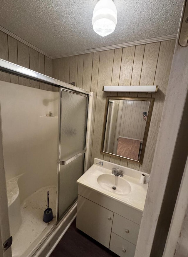 bathroom with vanity, wooden walls, a textured ceiling, and walk in shower