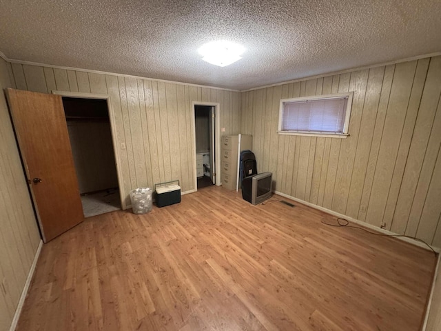 unfurnished bedroom with crown molding, a textured ceiling, and light wood-type flooring