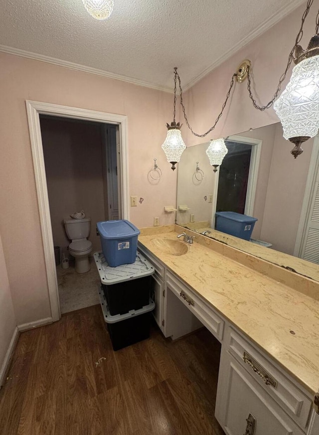 bathroom featuring wood-type flooring, ornamental molding, vanity, and a textured ceiling