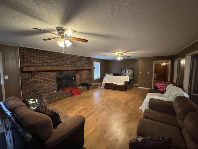 living room with wood-type flooring, ceiling fan, a textured ceiling, and a fireplace