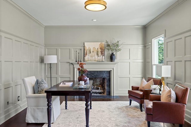 office area featuring dark wood-style floors, ornamental molding, a decorative wall, and a high end fireplace