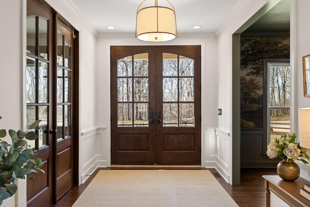 doorway to outside with a decorative wall, french doors, wainscoting, dark wood finished floors, and crown molding