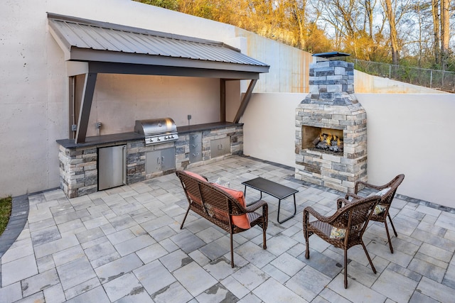 view of patio / terrace with an outdoor stone fireplace, a fenced backyard, a grill, and an outdoor kitchen