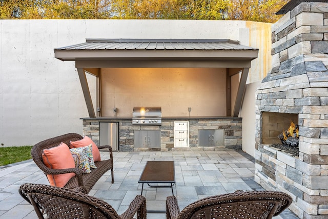 view of patio / terrace featuring an outdoor stone fireplace and area for grilling