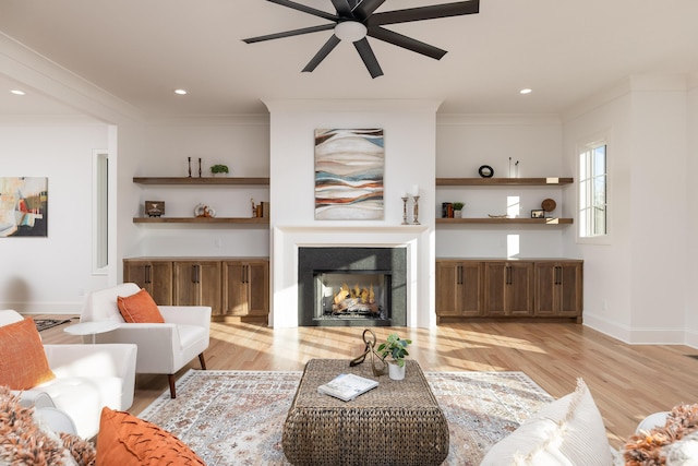 living area featuring light wood-style floors, a lit fireplace, and crown molding