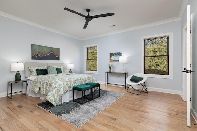 bedroom with light wood-style floors, baseboards, visible vents, and ornamental molding