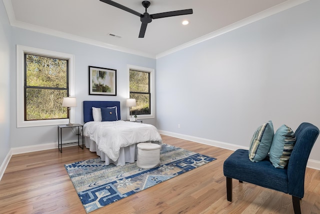 bedroom featuring baseboards, visible vents, wood finished floors, and ornamental molding