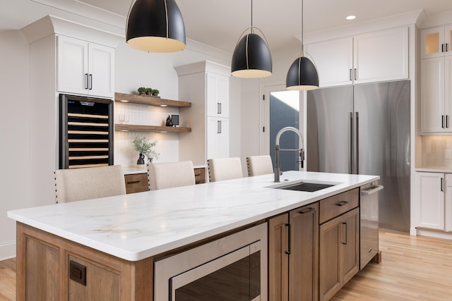 kitchen featuring stainless steel appliances, wine cooler, white cabinets, and a sink