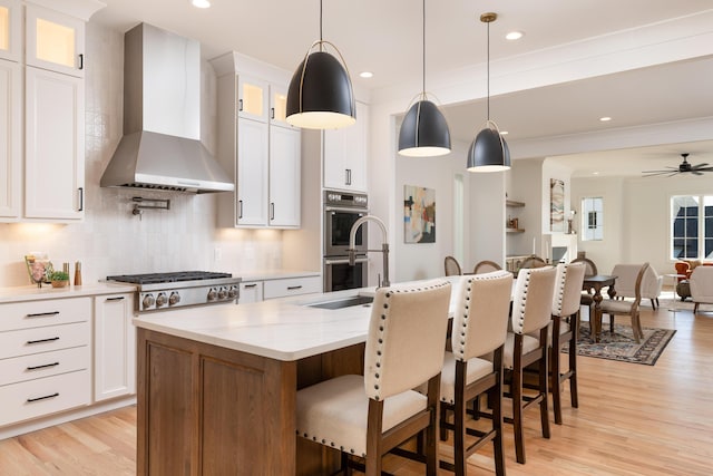 kitchen featuring glass insert cabinets, white cabinetry, wall chimney range hood, and appliances with stainless steel finishes