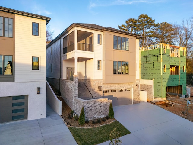 contemporary house with driveway, brick siding, an attached garage, and stucco siding