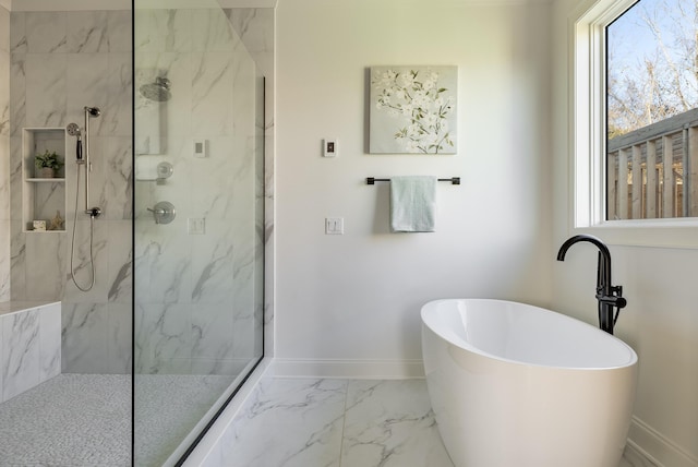 bathroom featuring plenty of natural light, marble finish floor, a freestanding tub, and a marble finish shower