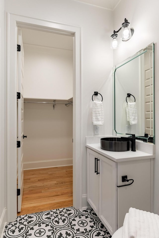 bathroom featuring a spacious closet, baseboards, wood finished floors, and vanity