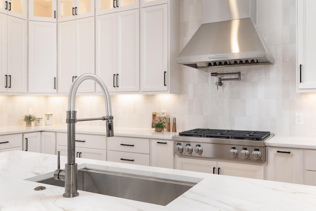 kitchen with white cabinets, wall chimney exhaust hood, glass insert cabinets, and stainless steel gas stovetop