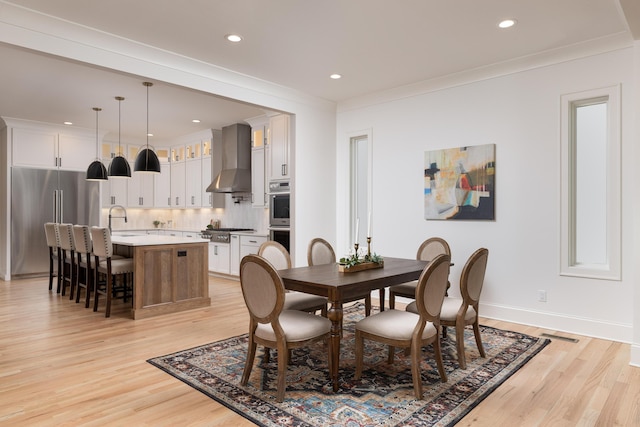 dining area featuring light wood-style flooring, baseboards, crown molding, and recessed lighting