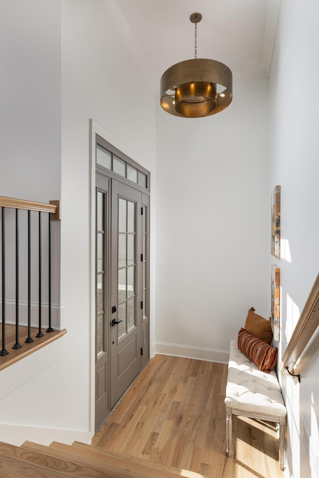 entryway with baseboards, crown molding, and light wood-style floors