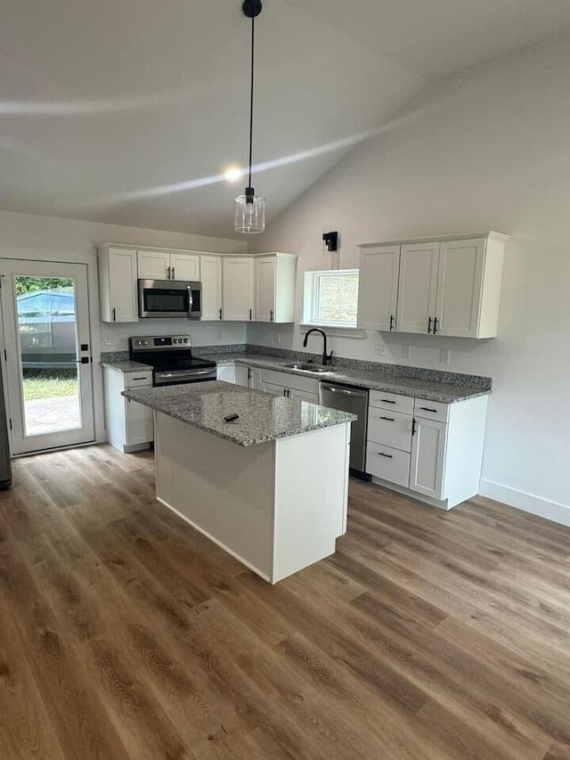 kitchen with a kitchen island, appliances with stainless steel finishes, decorative light fixtures, white cabinetry, and sink