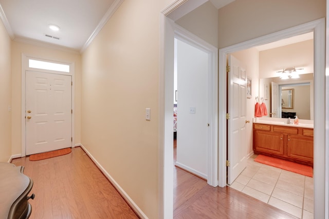 foyer entrance featuring ornamental molding and light hardwood / wood-style flooring