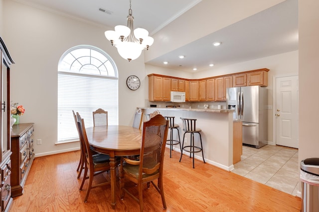 dining area with light wood-type flooring, crown molding, and a notable chandelier