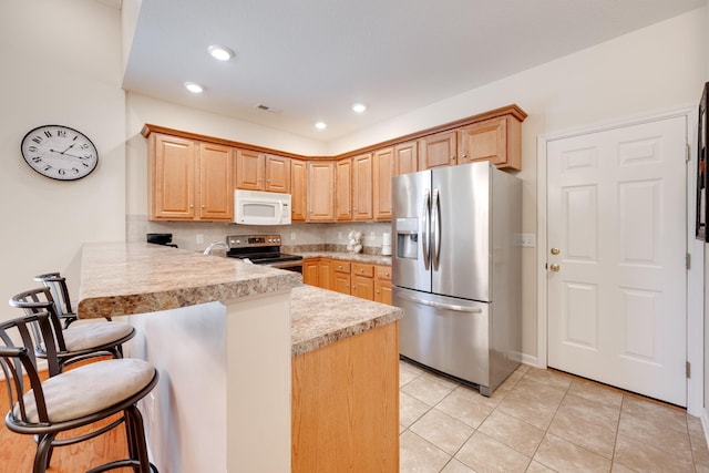 kitchen featuring light brown cabinetry, a breakfast bar area, stainless steel appliances, decorative backsplash, and kitchen peninsula