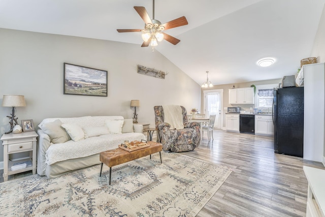 living room featuring ceiling fan, vaulted ceiling, and light hardwood / wood-style flooring