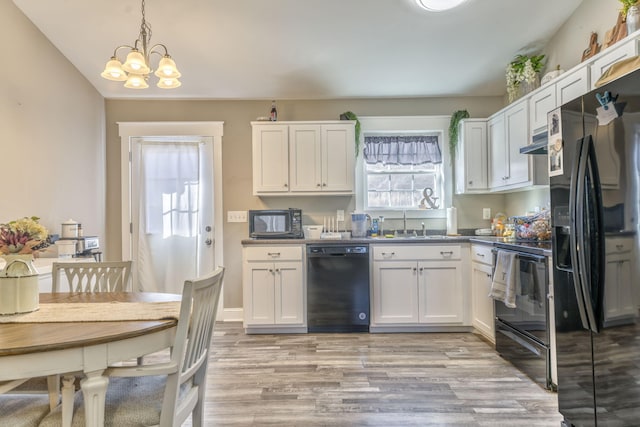 kitchen featuring black appliances, light hardwood / wood-style flooring, hanging light fixtures, a notable chandelier, and white cabinets