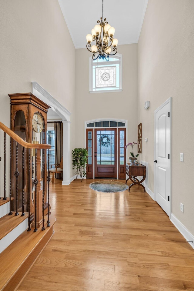 foyer with a towering ceiling, a chandelier, and light hardwood / wood-style flooring