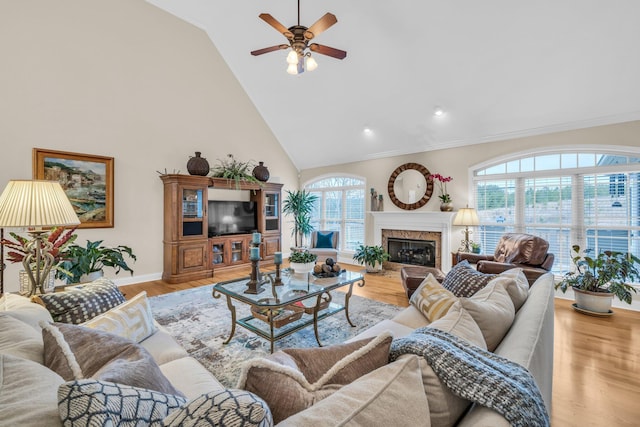 living room featuring ceiling fan, high vaulted ceiling, a high end fireplace, and light hardwood / wood-style floors