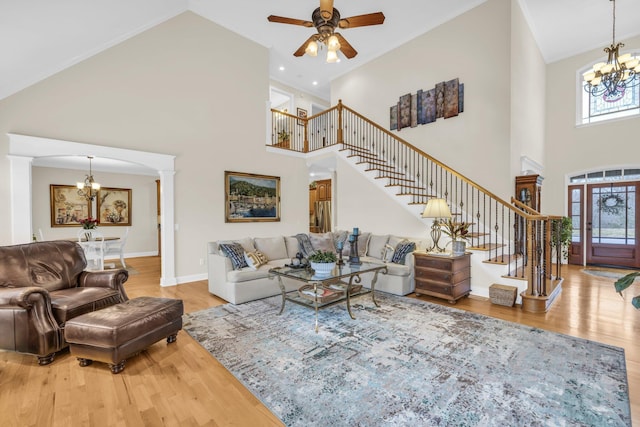 living room with hardwood / wood-style flooring, a healthy amount of sunlight, ceiling fan with notable chandelier, and a towering ceiling