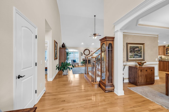 entrance foyer with ceiling fan, high vaulted ceiling, decorative columns, ornamental molding, and light wood-type flooring