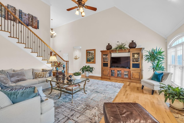 living room with hardwood / wood-style flooring, ceiling fan with notable chandelier, and high vaulted ceiling