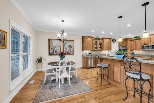 dining area with crown molding, a chandelier, and light wood-type flooring