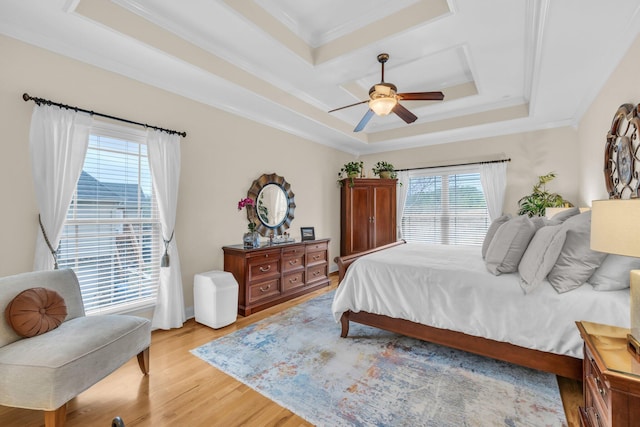 bedroom featuring a raised ceiling, multiple windows, and light wood-type flooring