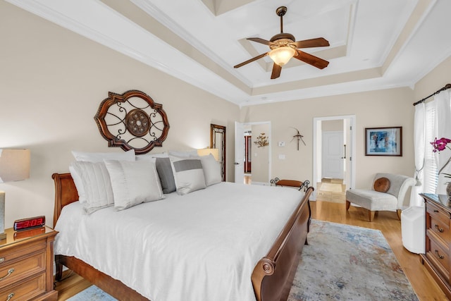 bedroom featuring crown molding, ceiling fan, light wood-type flooring, and a tray ceiling