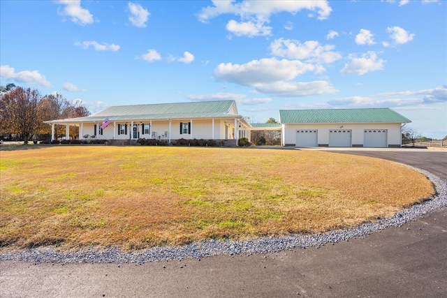 view of front of home with a garage, metal roof, an outdoor structure, and a front yard