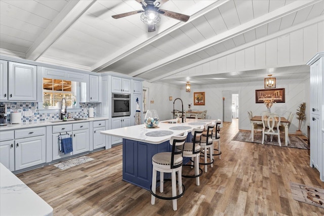 kitchen with vaulted ceiling with beams, light countertops, a sink, and oven