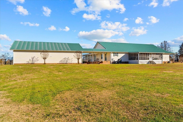 back of house with a sunroom, metal roof, and a yard