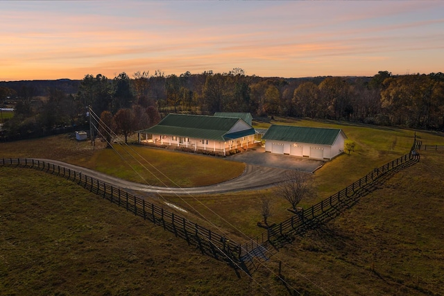 aerial view at dusk with a rural view and a wooded view