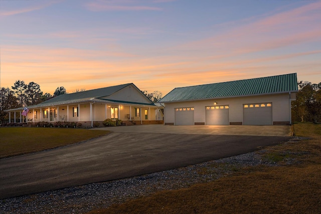 view of front of house with an outbuilding, a front yard, metal roof, a garage, and driveway