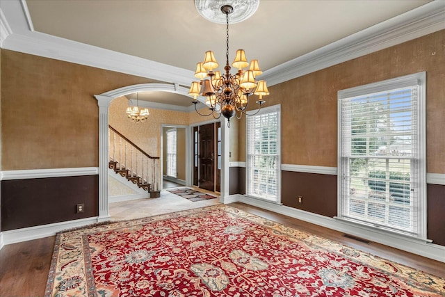 spare room with ornamental molding, wood-type flooring, and a notable chandelier