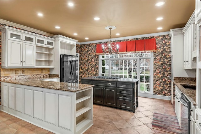 kitchen with hanging light fixtures, white cabinetry, black refrigerator, and stainless steel gas cooktop