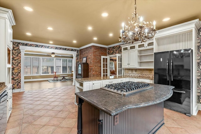 kitchen with black fridge, white cabinetry, hanging light fixtures, and a kitchen island