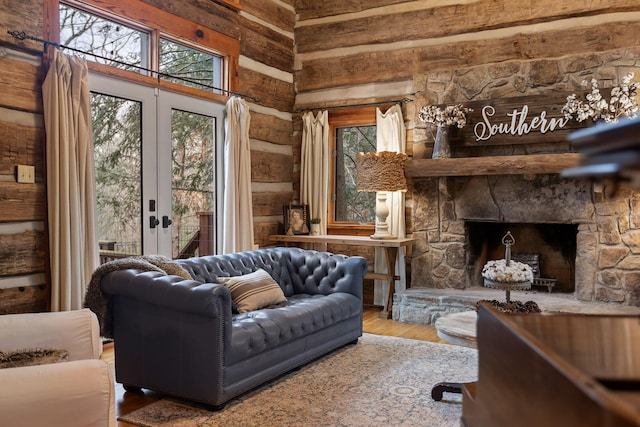 living room featuring rustic walls, a stone fireplace, a wealth of natural light, and hardwood / wood-style floors