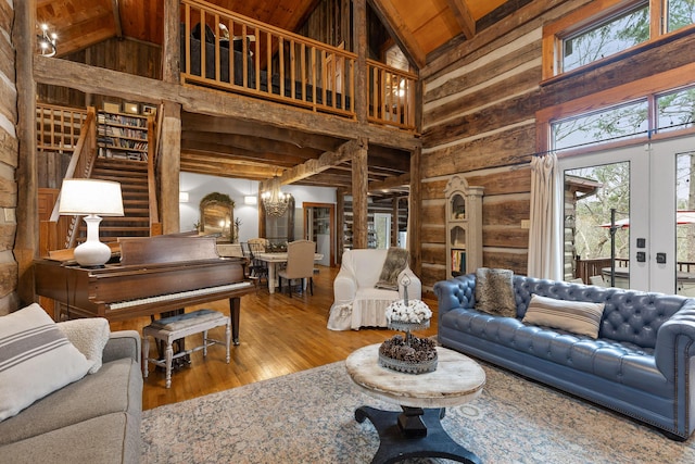 living room featuring french doors, beamed ceiling, a notable chandelier, wooden ceiling, and hardwood / wood-style floors