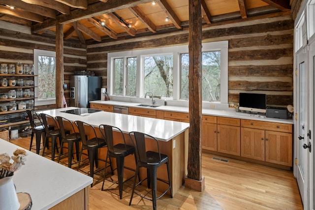 kitchen with a center island, light hardwood / wood-style floors, lofted ceiling with beams, appliances with stainless steel finishes, and a breakfast bar area