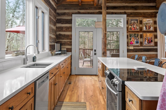 kitchen featuring rustic walls, sink, stainless steel appliances, and light hardwood / wood-style floors